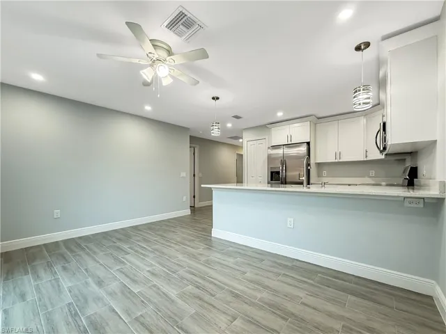 Kitchen with hanging light fixtures, appliances with stainless steel finishes, white cabinetry, a peninsula, and recessed lighting