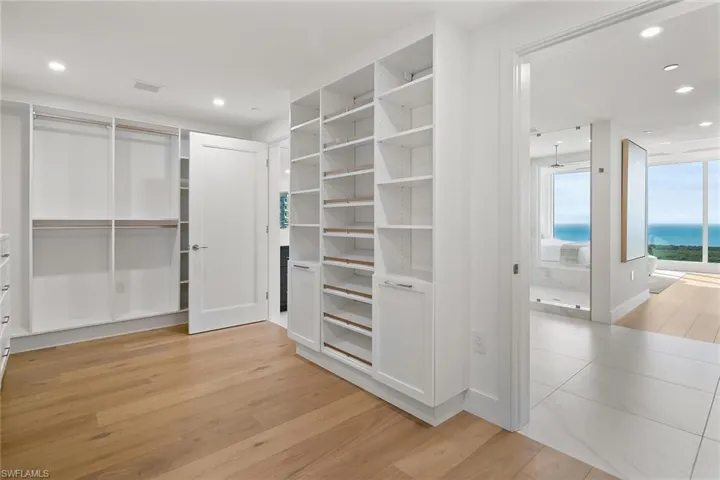 Generous custom built-in primary closet filled with natural light and open to spectacular water views