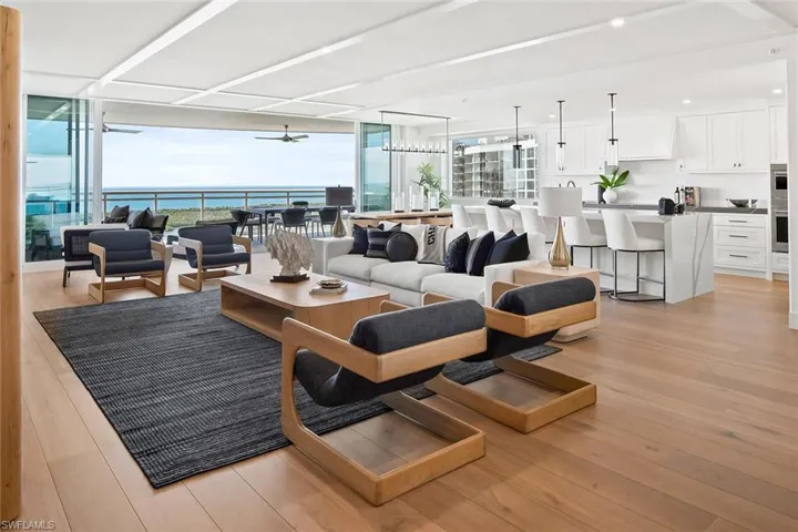 Furnished 22nd-floor great room with expansive big-water views, featuring impact-rated pocketing doors that open wide to the terrace for seamless indoor-outdoor living