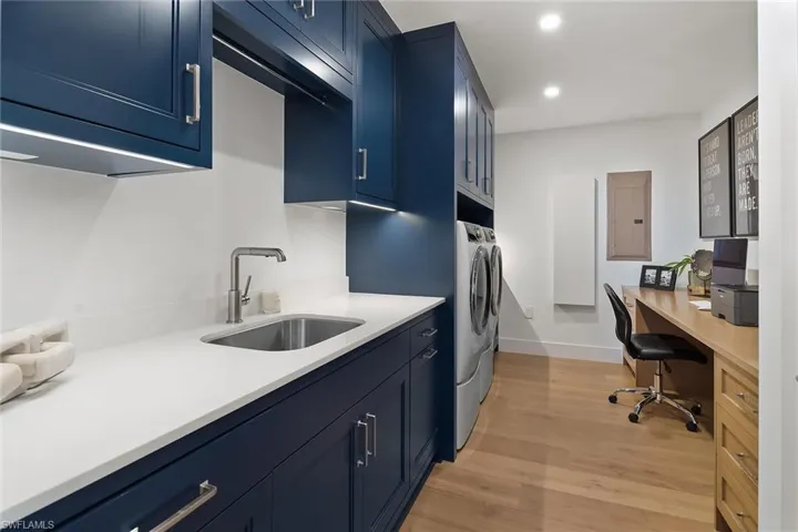 Laundry room designed with custom cabinetry, quartz surfaces, an Iron-A-Way, and a utility closet