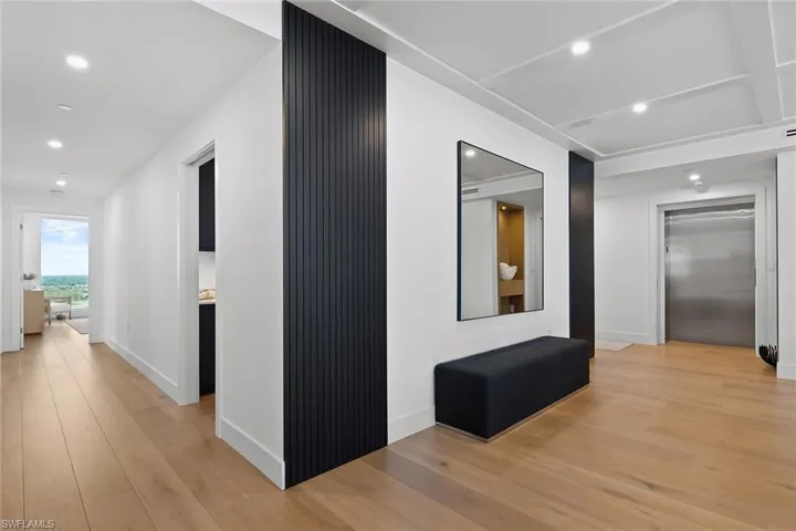 Private elevator entry featuring a striking wood accent wall and two hallways leading to guest suites laundry/office and den