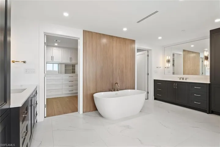 Spa-style bath featuring a soaking tub, his-and-hers storage, and a striking warm wood accent wall
