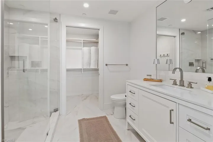 Elegant en-suite bath highlighted by a glass walk-in shower, quartz finishes, and custom built-in closet