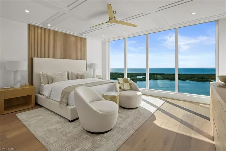 Furnished king-size primary bedroom with a wall of windows framing breathtaking Gulf and bay views