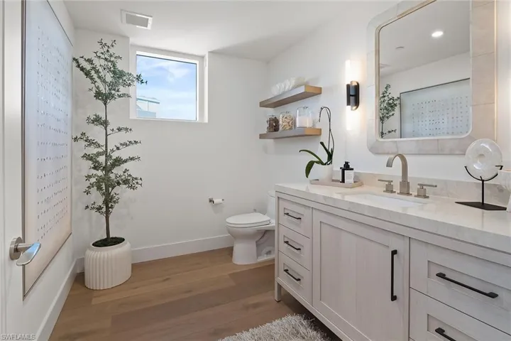 Elegant powder room enhanced by a Gulf-view window and beautiful natural light.