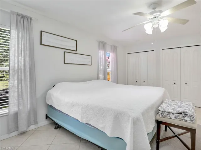 Tiled bedroom featuring ceiling fan and multiple closets