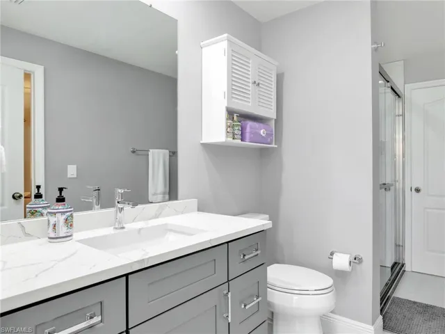 Bathroom featuring tile floors, walk in shower, oversized vanity, and toilet