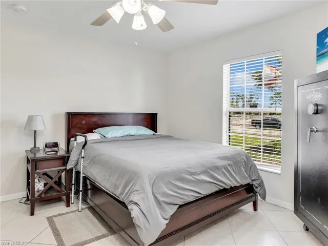 Tiled bedroom with ceiling fan and multiple windows