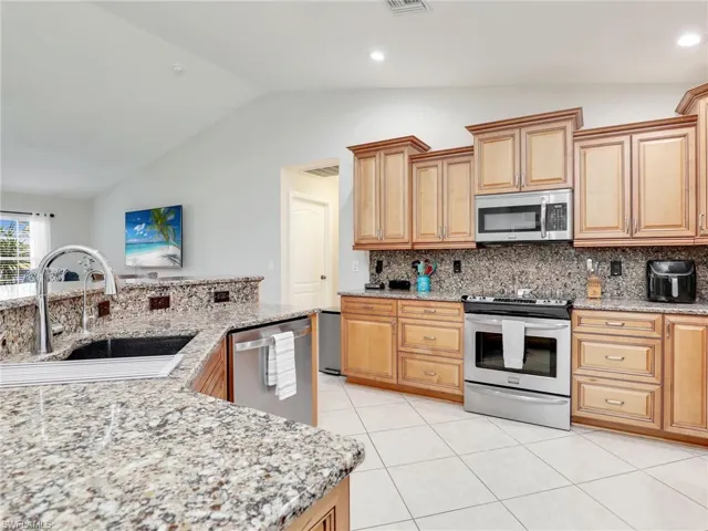 Kitchen featuring appliances with stainless steel finishes, sink, vaulted ceiling, and backsplash