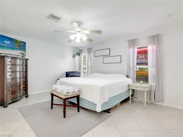 Tiled bedroom featuring multiple windows and ceiling fan