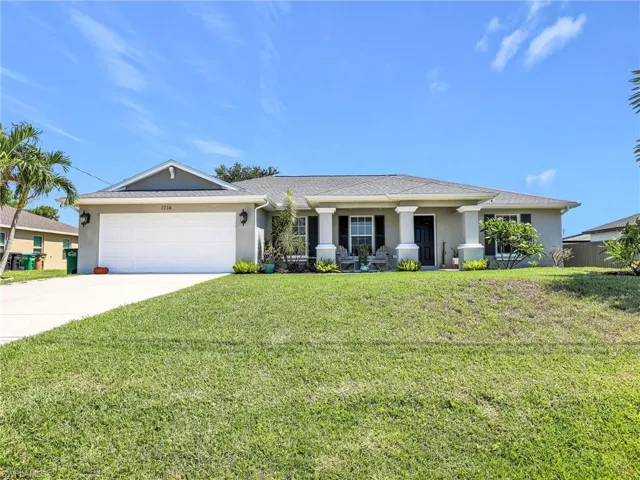 View of front of property with a front yard and a garage