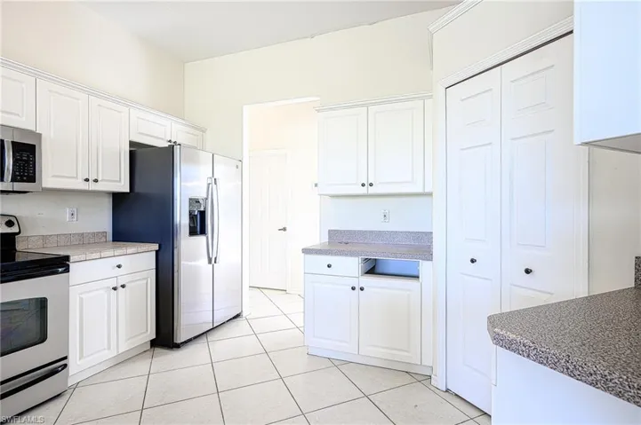 Kitchen featuring stainless steel appliances, solid surface countertops, white cabinetry, and light tile patterned floors- walk in Pantry as well!!