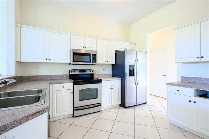 Kitchen with light tile patterned floors, appliances with stainless steel finishes, light countertops, white cabinetry, and a sink- In great shape!