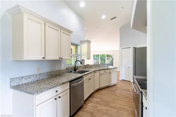Kitchen featuring light stone counters, light wood-type flooring, stainless steel appliances, recessed lighting, and a peninsula