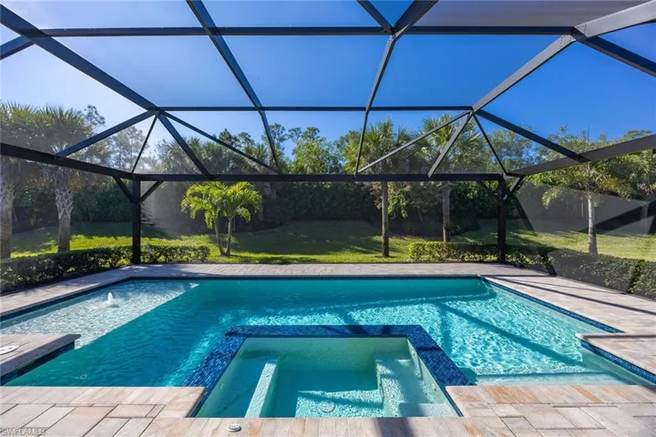 View of swimming pool featuring a pool with connected hot tub, a sunroom, and glass enclosure