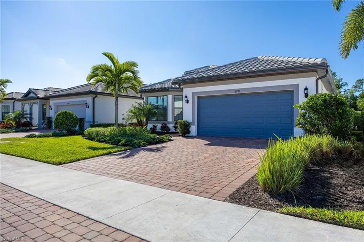 View of front of home with stucco siding, decorative driveway, an attached garage, and a tiled roof
