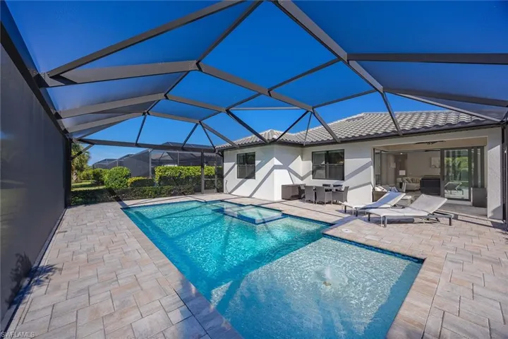 View of pool with a sunroom, a patio, glass enclosure, and a pool with connected hot tub