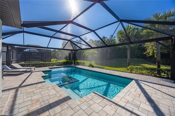 View of swimming pool with a pool with connected hot tub, glass enclosure, a sunroom, and a patio area