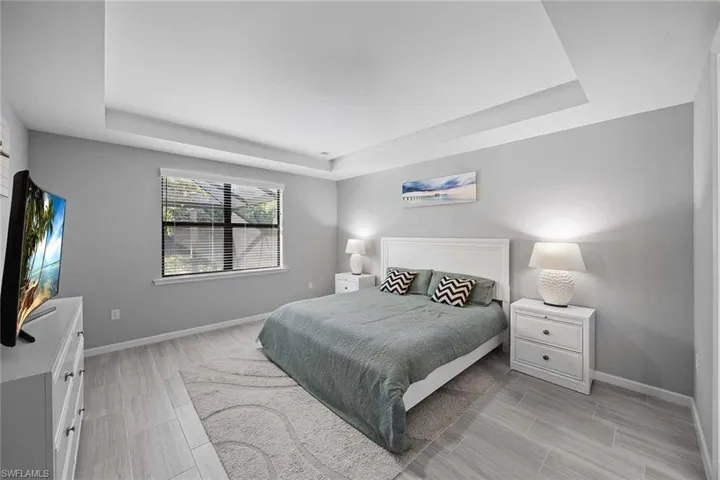 Bedroom featuring a tray ceiling and wood finish floors