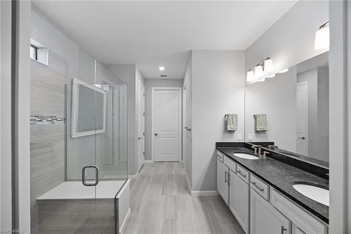Full bath with double vanity, a stall shower, and recessed lighting