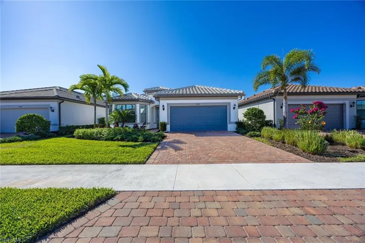 View of front of house with stucco siding, decorative driveway, a garage, a front yard, and a tiled roof