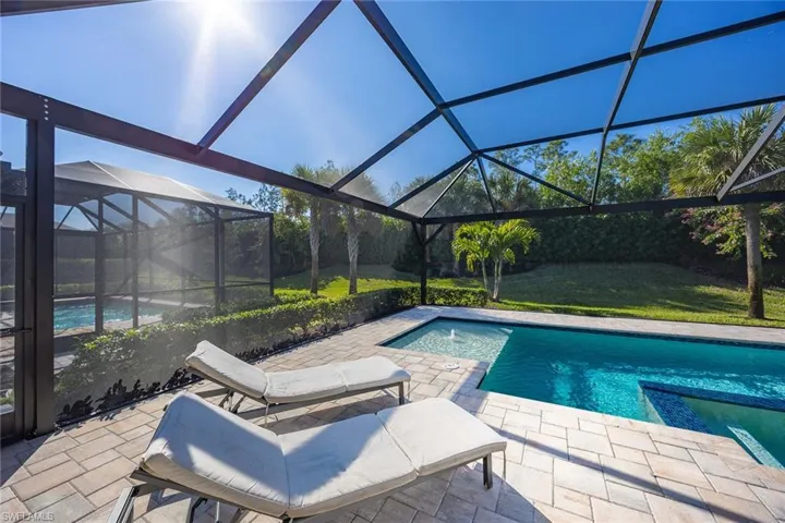 View of pool with glass enclosure, a pool with connected hot tub, a sunroom, and a patio area