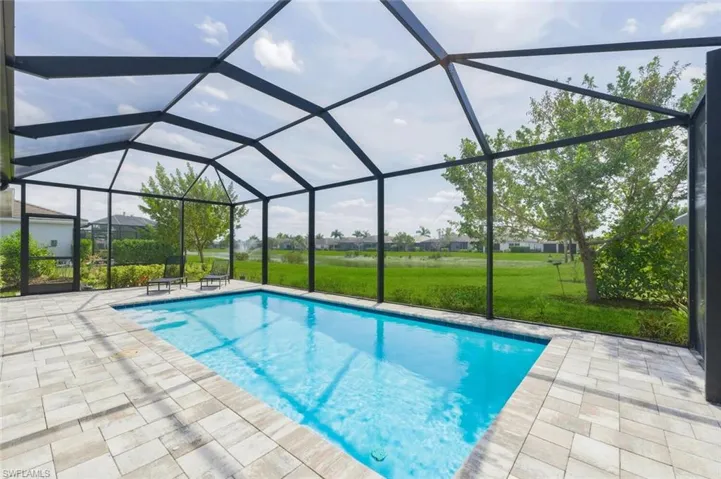 Swimming pool featuring a sunroom, glass enclosure, a yard, and a residential view