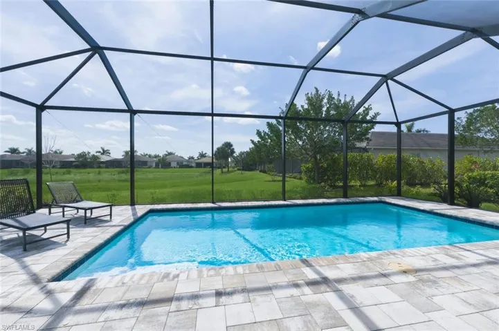 Outdoor pool with a sunroom, glass enclosure, a lawn, and a residential view
