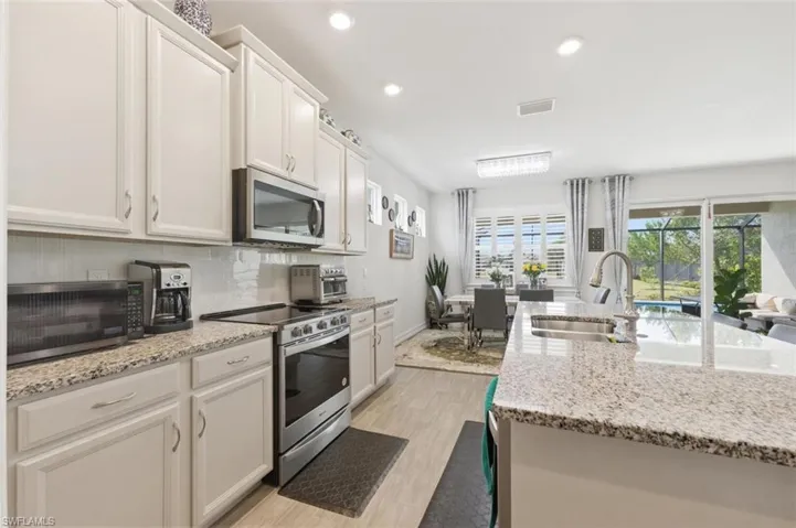 Kitchen with stainless steel appliances, recessed lighting, light stone countertops, light wood-style floors, and white cabinets