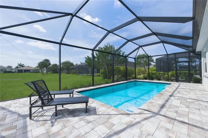 Outdoor pool with a sunroom, a lanai, a yard, and a patio