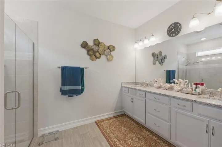 Full bathroom with a stall shower, double vanity, and wood tiled floors