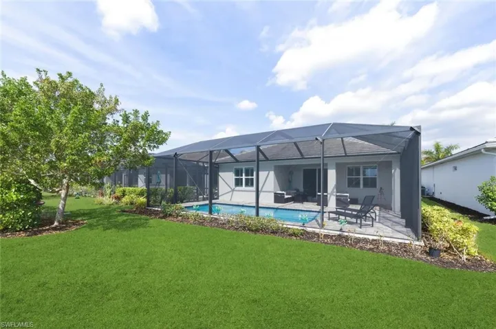 Back of house featuring a sunroom, a yard, an outdoor pool, a lanai, and a patio area