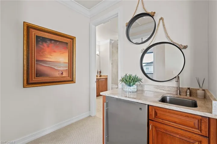 Bar featuring a sink, crown molding, stainless steel fridge, light carpet, and baseboards