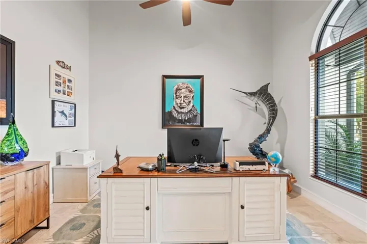 Office with a ceiling fan and baseboards