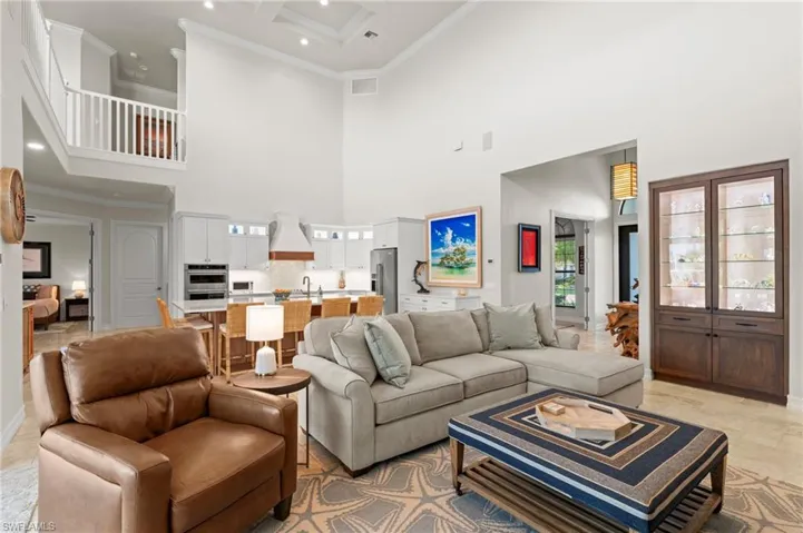 Living room featuring a towering ceiling, ornamental molding, recessed lighting, and baseboards