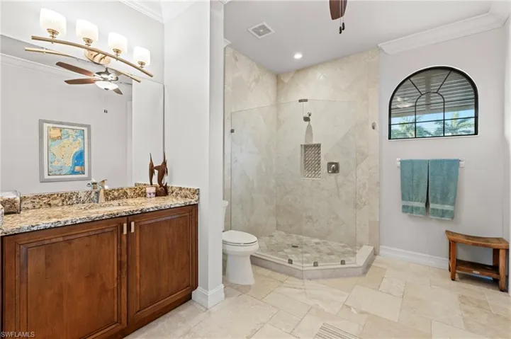Full bathroom with a ceiling fan, ornamental molding, baseboards, toilet, and a stall shower