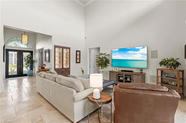 Living area featuring a towering ceiling, crown molding, and french doors