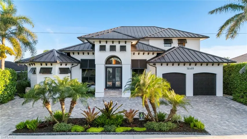 View of front facade with french doors, a standing seam roof, a garage, and metal roof