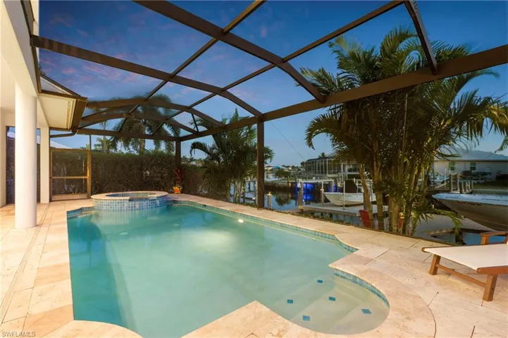 View of swimming pool with a patio, a lanai, a dock, a pool with connected hot tub, and boat lift