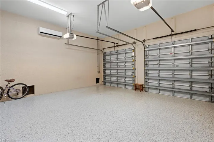 Garage featuring a garage door opener and a wall unit AC