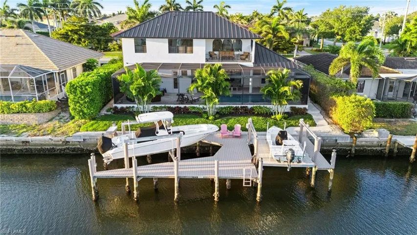 Dock area featuring boat lift, a water view, a balcony, a patio, and a lanai