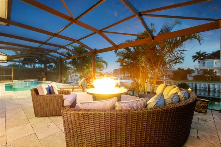 View of patio / terrace featuring glass enclosure, a pool with connected hot tub, and an outdoor fire pit