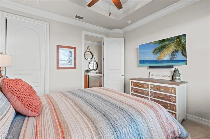 Bedroom with crown molding, a tray ceiling, carpet flooring, ceiling fan, and baseboards