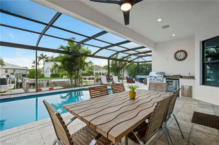 Outdoor pool featuring an outdoor kitchen, a patio area, a grill, and glass enclosure