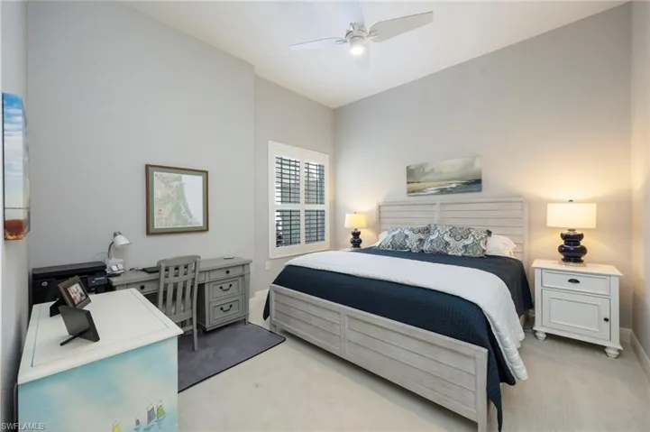 Bedroom with light carpet, a ceiling fan, and a desk
