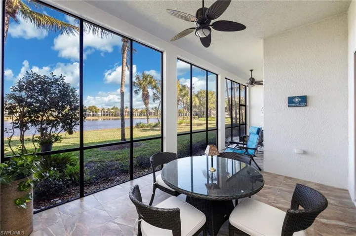 Lanai featuring a textured wall, a water view, a ceiling fan, outdoor dining area, and a textured ceiling and tiled floor