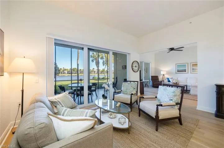 Living room featuring light wood-style flooring, a water view, and a ceiling fan
