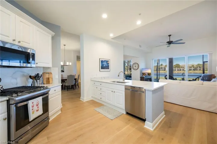 Kitchen featuring stainless steel appliances, white cabinetry, open floor plan, recessed lighting, and light wood-style floors