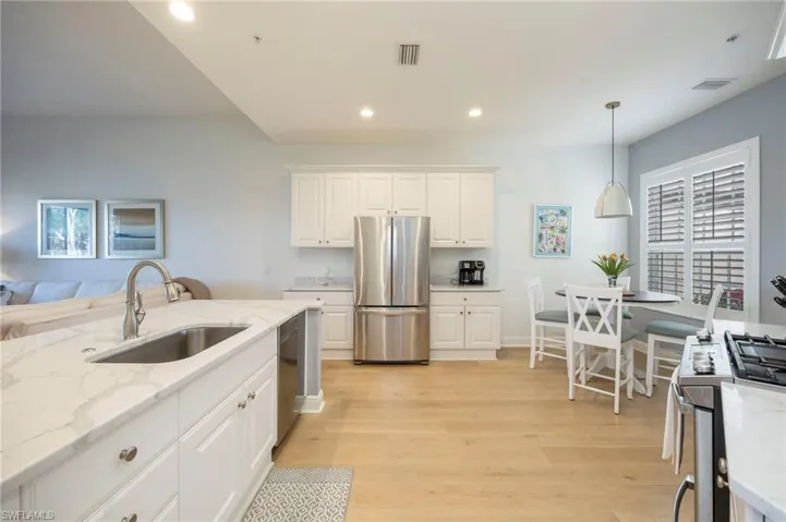 Kitchen featuring white cabinets, light stone countertops, stainless steel appliances, healthy amount of natural light, and recessed lighting