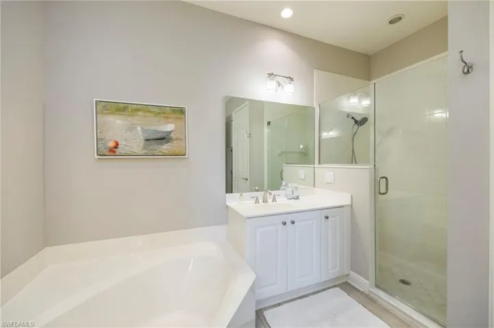 Bathroom featuring a shower stall, a bath, and vanity